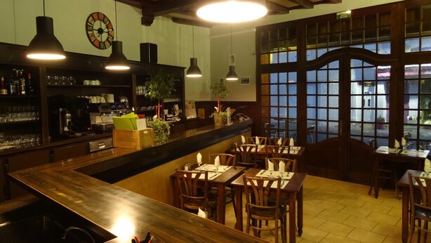 En restaurant med barområde, træborde og stole samt store vinduer med udsigt.