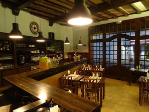 Un restaurante con barra, mesas y sillas de madera, y amplios ventanales con vistas.