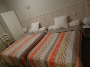 A room with two beds, each with striped bedding and white pillows.
