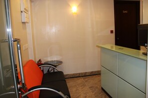 A small, compact room with a single bed, a bedside table, a chair, and a small table. - Joyous Guest House (Kowloon)