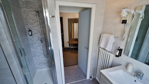 A modern bathroom with a glass shower enclosure, a white sink, and a towel rack. - Hôtel de l'Europe Grenoble Hyper Centre (Grenoble)