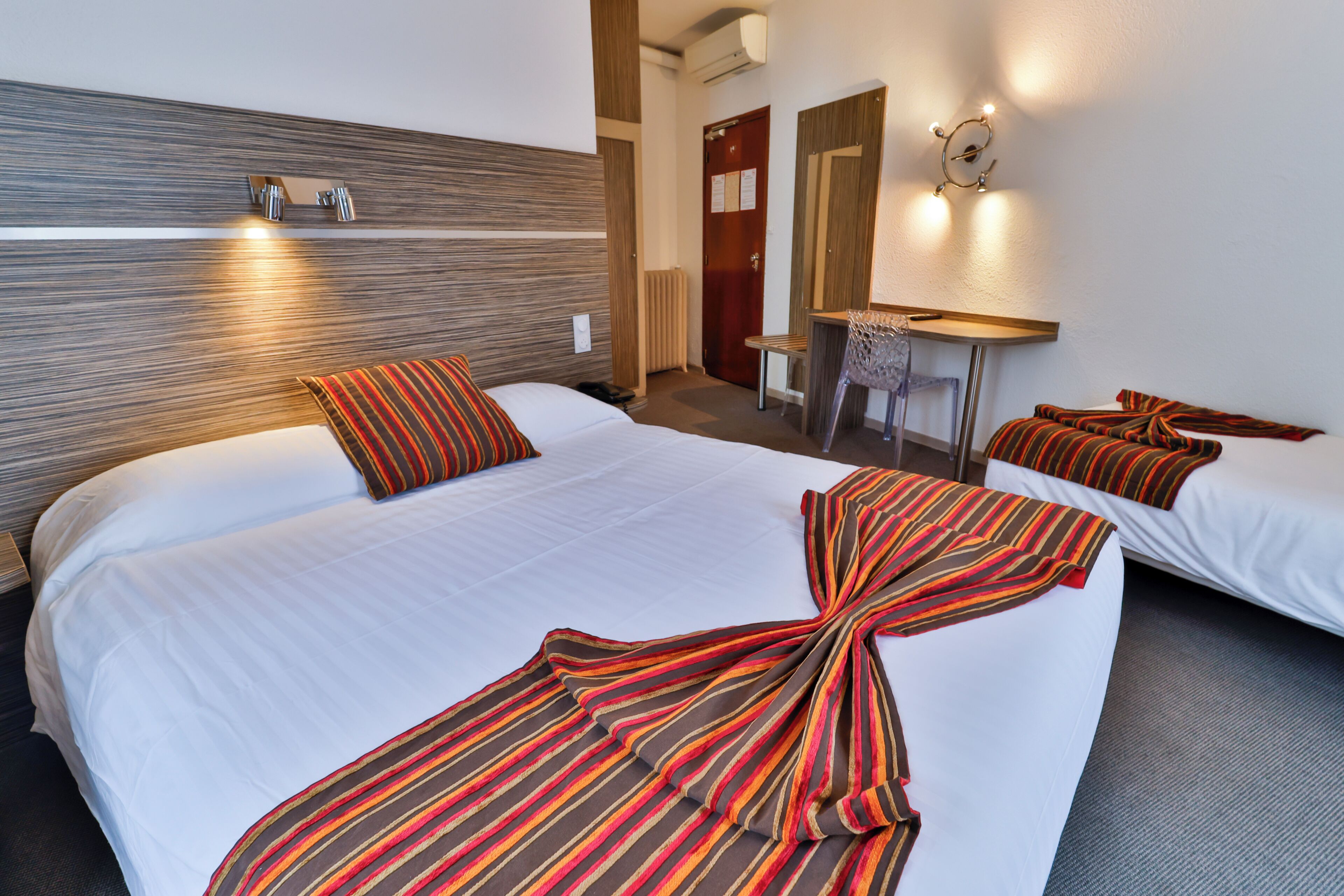A hotel room with a large bed, a desk, and a chair.