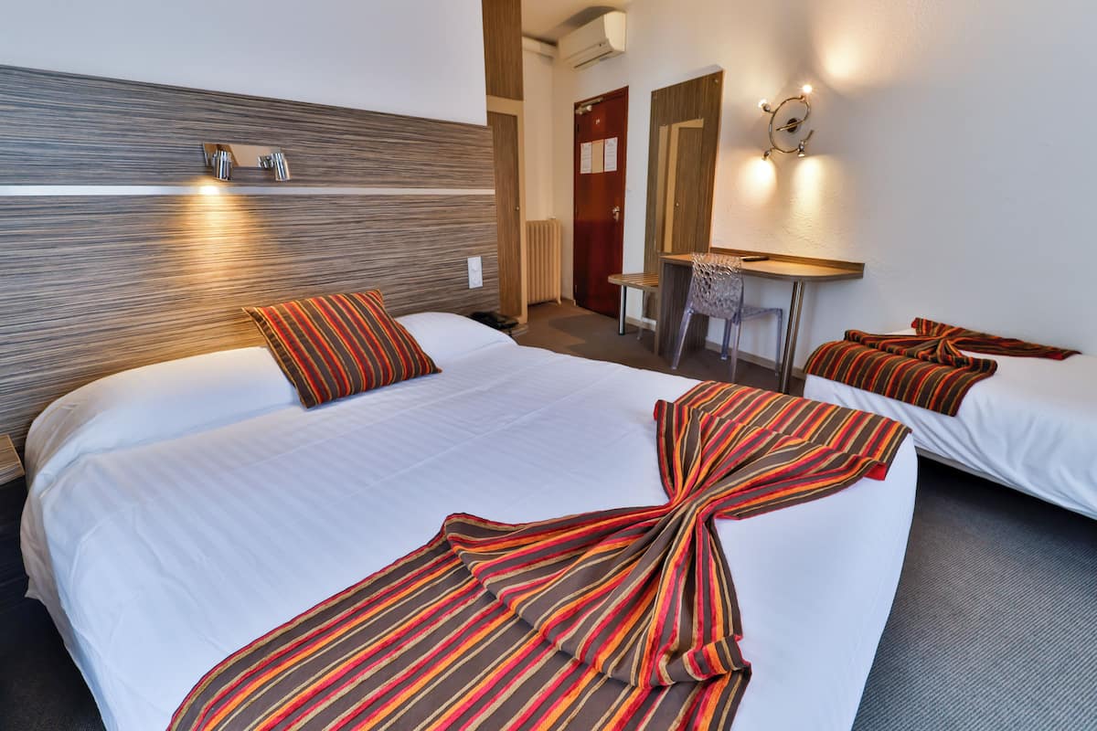 A hotel room with a large bed, a desk, and a chair.