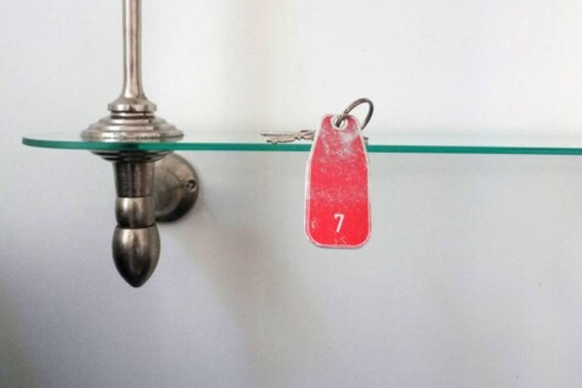A metal light fixture with a glass shelf and a red tag with the number 7.