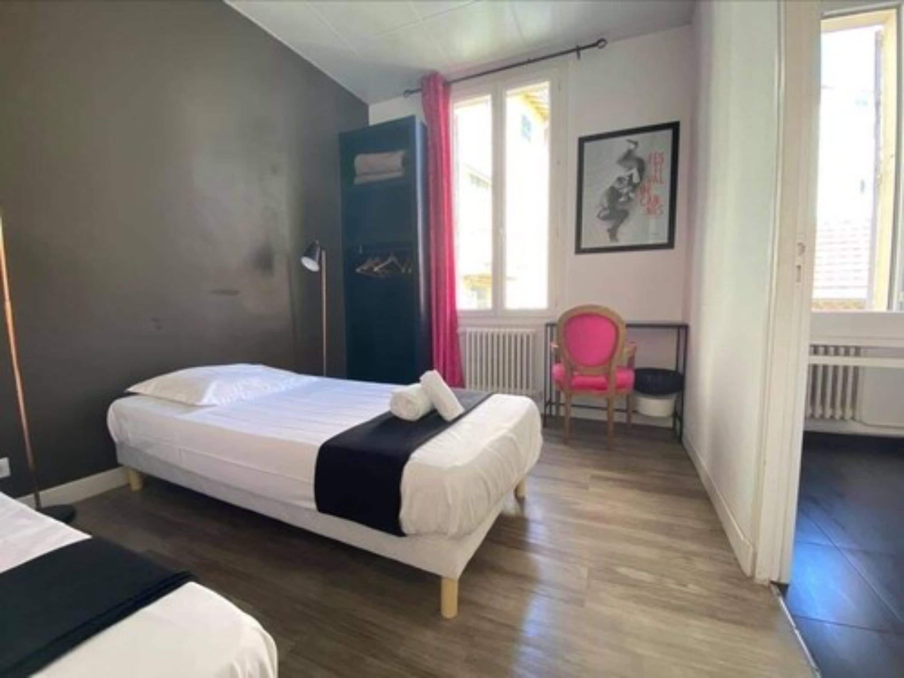 Un dormitorio con cama, una silla, un radiador y una ventana.