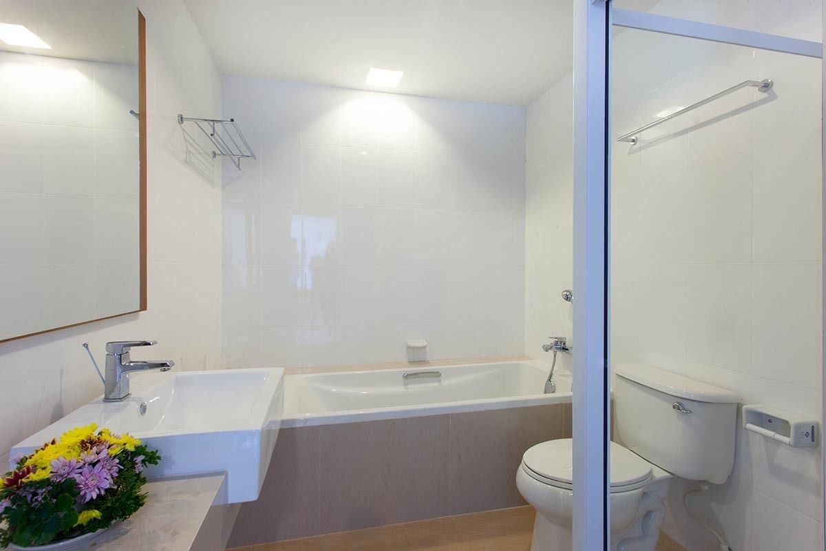 Un baño moderno con una bañera grande, un inodoro y un lavabo con un arreglo floral.