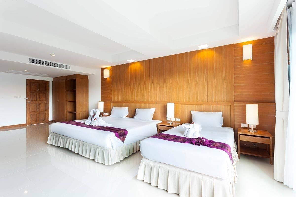 Habitación de hotel con dos camas, paneles de madera en las paredes y un ventanal grande.