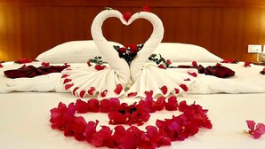 A bed with a heart-shaped arrangement of white towels and red rose petals, suggesting a romantic setting. - Rawai Princess Hotel (Rawai)