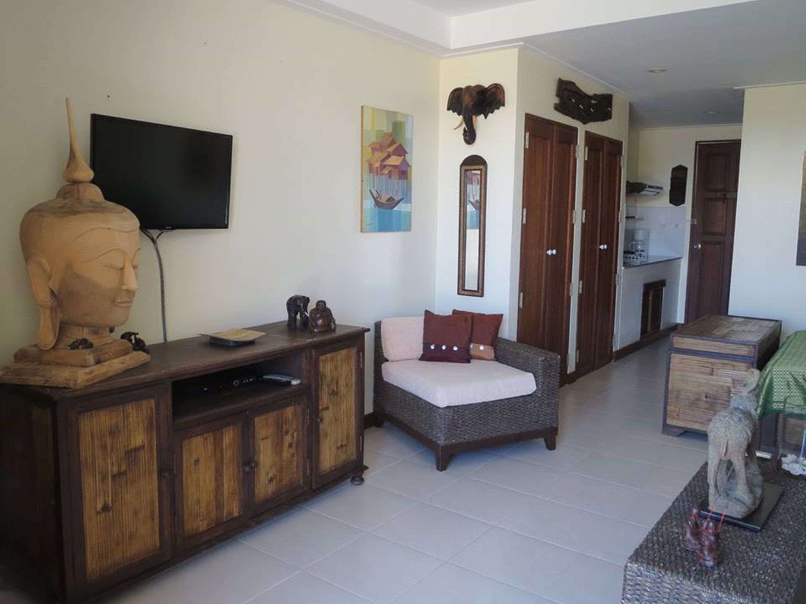 A living room with a wooden cabinet, a television, a sofa, and a statue.