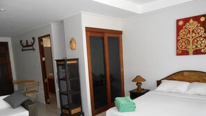 Una habitación de hotel con cama, escritorio, silla, armario y un adorno en la pared.