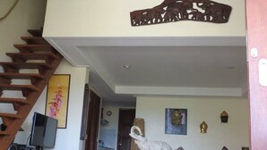 Amplia sala de estar con techo alto, escalera de madera y una escultura decorativa de elefante.