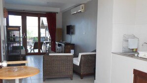 Un espacio habitable compacto con zona de comedor, un sofá, televisión y cocina.