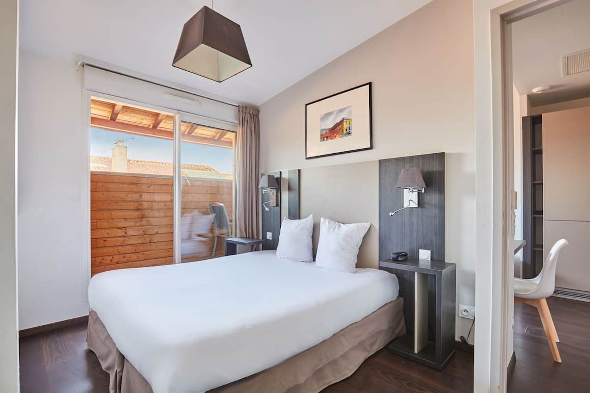 Ein Hotelzimmer mit einem großen Bett, einem Schreibtisch, einem Stuhl, einer Lampe und einem Bild an der Wand.