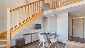 A modern kitchen with a dining table, chairs, a TV, and a staircase. - Odalys City Apartment Hotel - Toulouse Centre Gare (Toulouse)