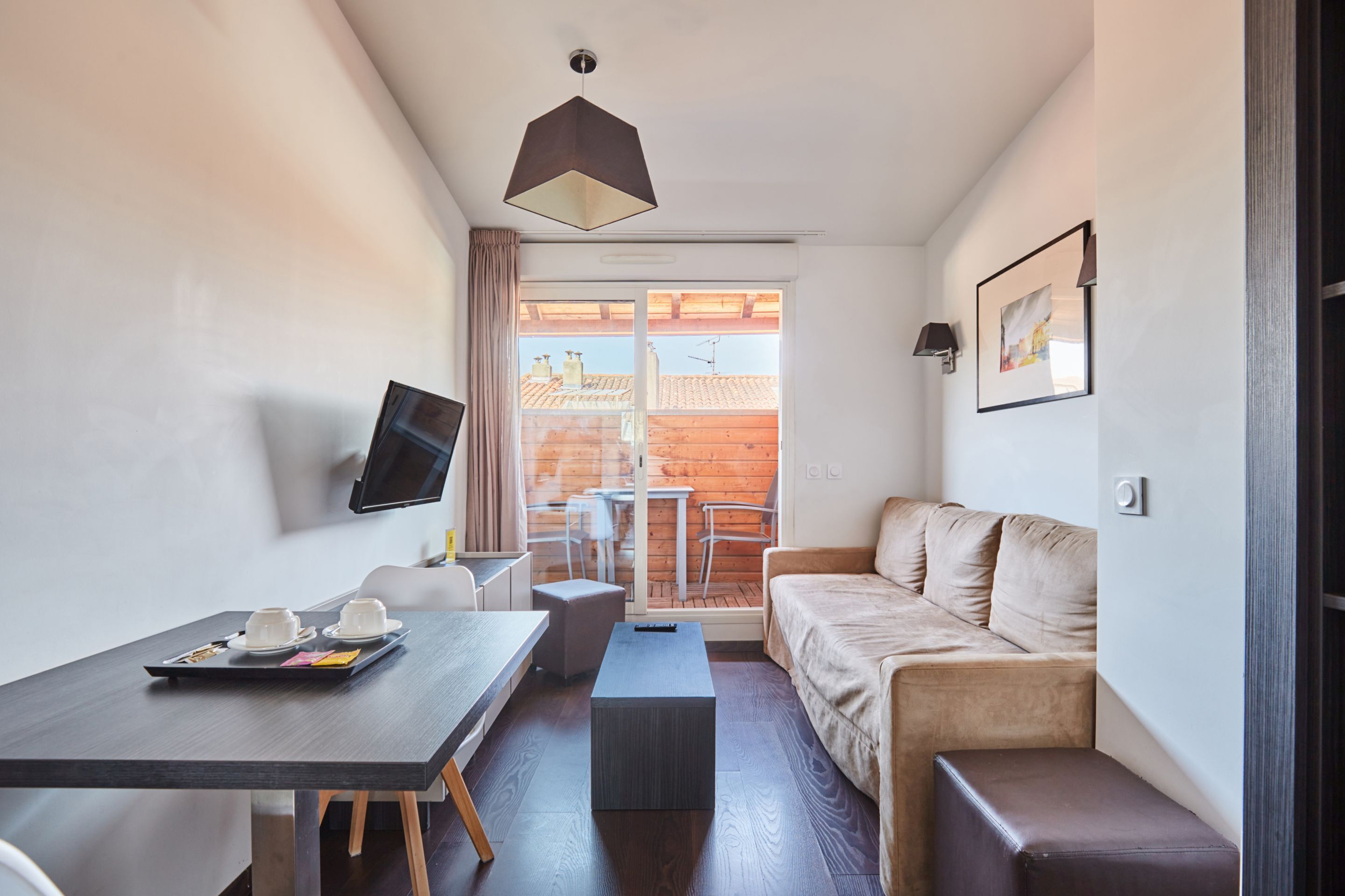 Een moderne woonkamer met een bank, een salontafel, een aan de muur bevestigde televisie en een eethoek met een tafel en stoelen.