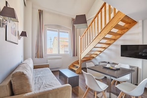 A modern living space with a sofa, dining table, chairs, a staircase, and a TV. - Odalys City Apartment Hotel - Toulouse Centre Gare (Toulouse)