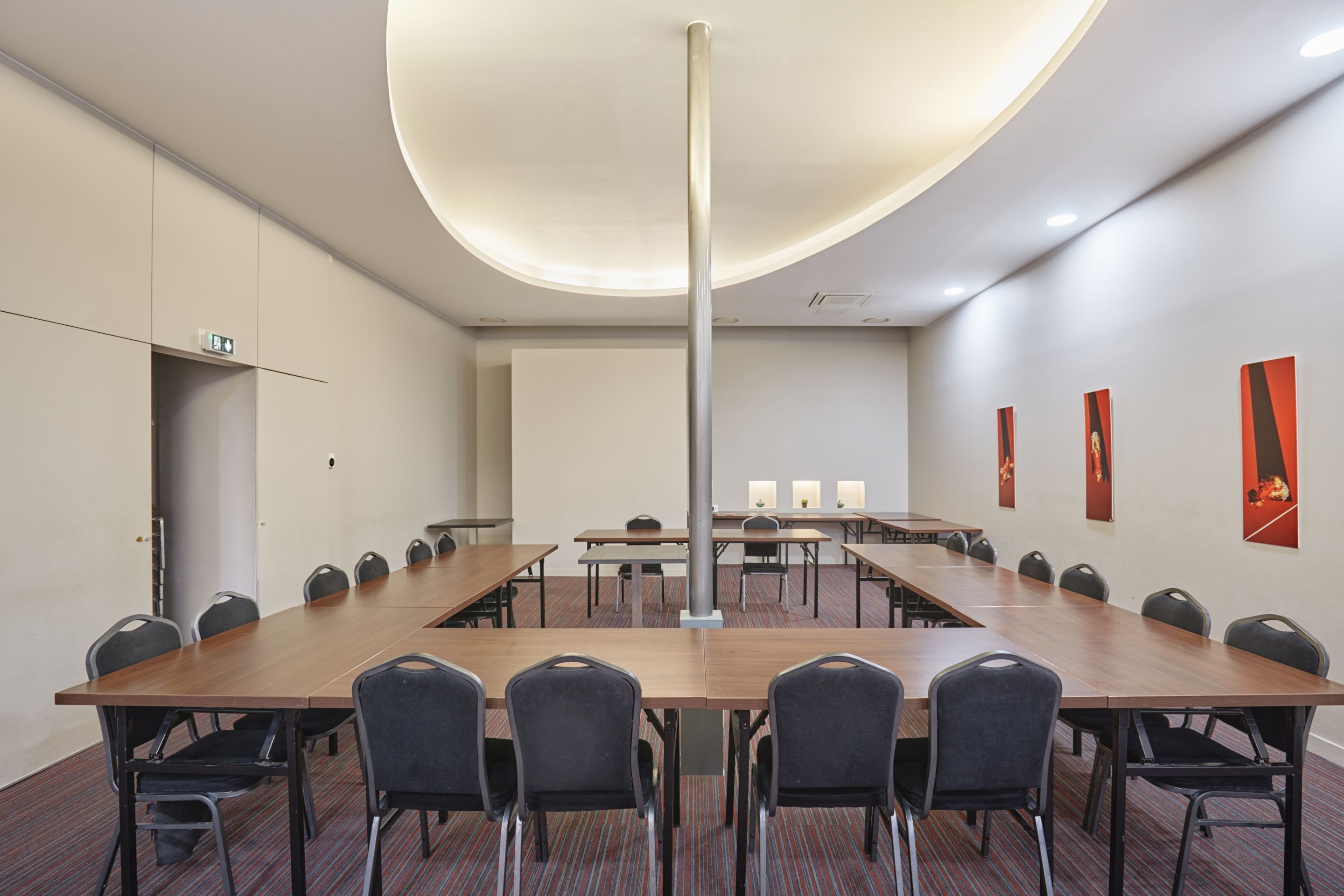 Un salón de conferencias con una larga mesa, sillas, un proyector y una pizarra.
