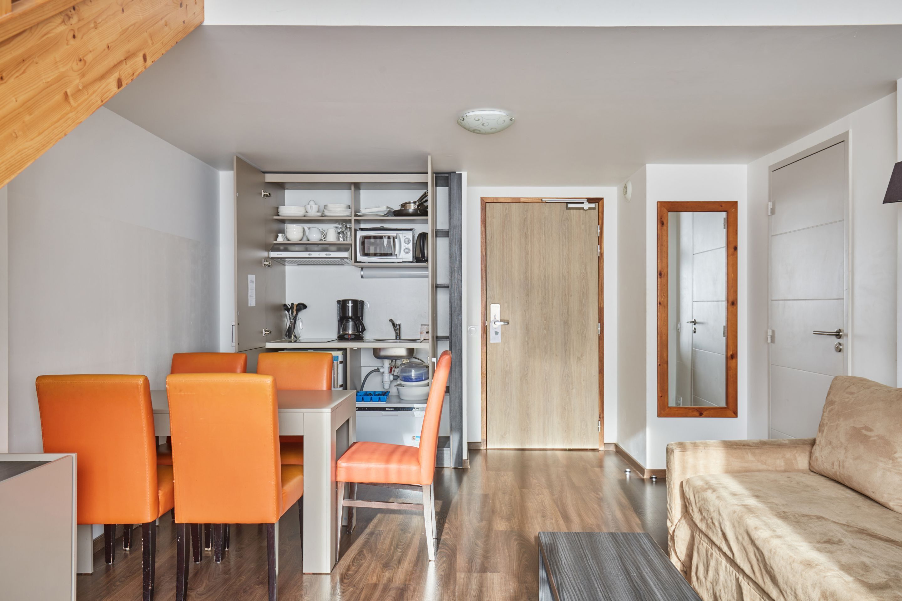 Een knus woongedeelte met een kitchenette, eethoek en een bank.