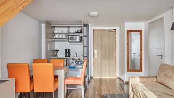 Een knus woongedeelte met een kitchenette, eethoek en een bank.