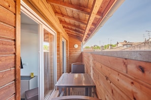 Uma cabana de madeira com varanda, uma mesa e uma cadeira.