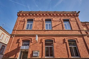 Ein rot gebackenes Gebäude mit einem Schild, auf dem 'Odalys' steht, und einem sichtbaren Geldautomaten.