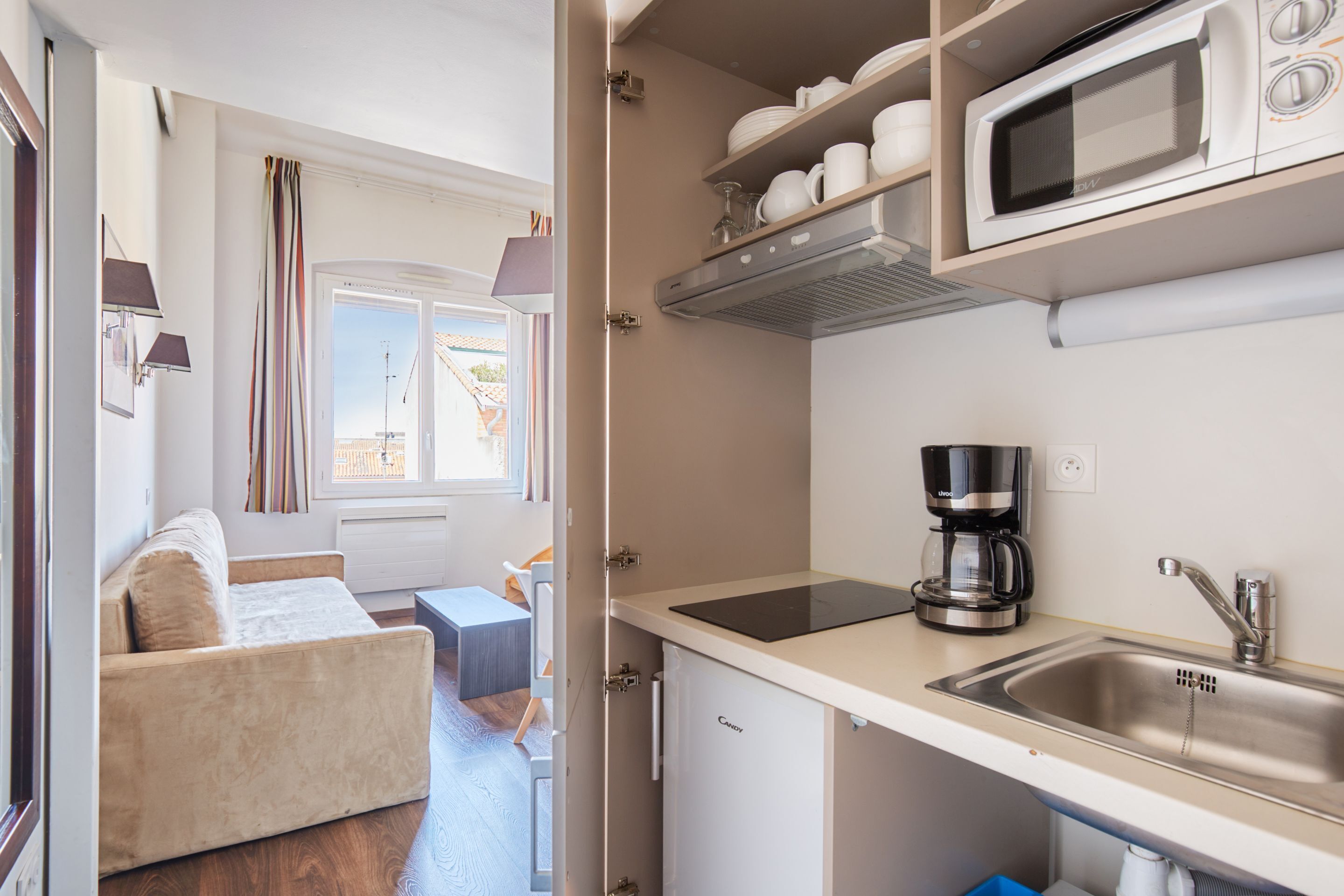 A compact kitchen with a microwave, coffee maker, and a sink.
