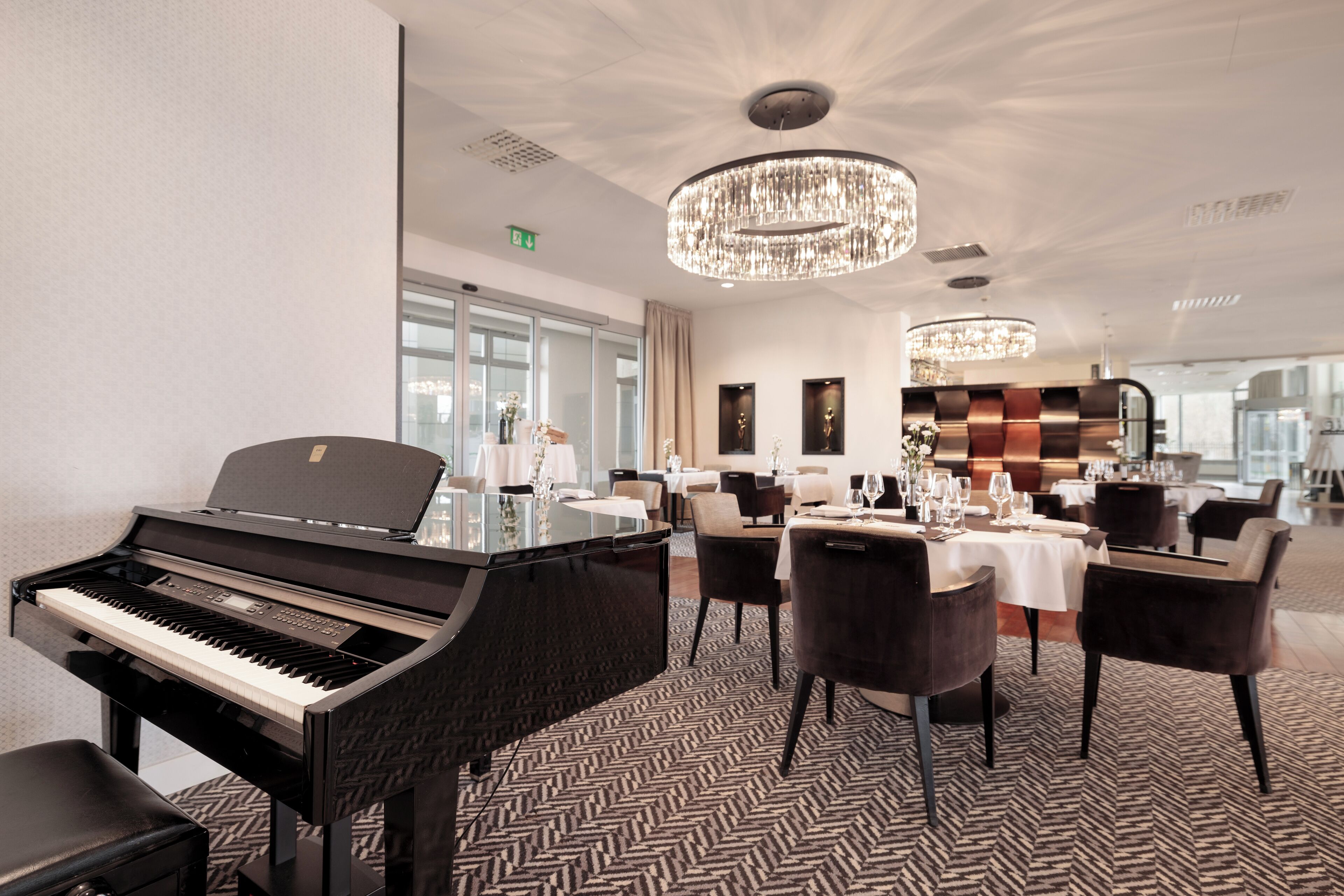 Un comedor de hotel con un piano de cola, candelabros modernos y una decoración de diseño contemporáneo.