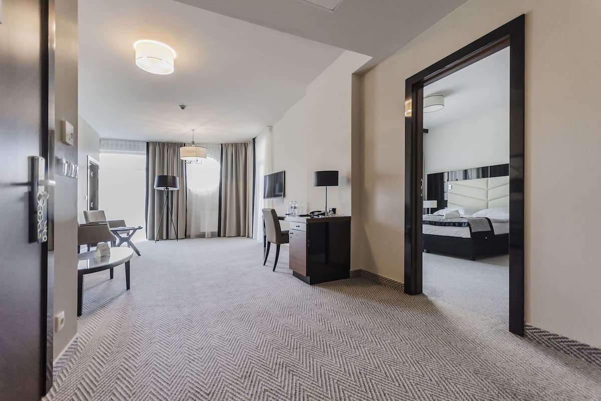 Une chambre d’hôtel avec un lit, un bureau, une chaise et un grand miroir.