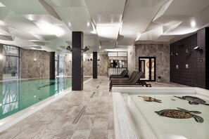 A modern indoor swimming pool with a clear view of the pool area, a separate hot tub with turtle designs, and a spa area with seating. - Diune Resort (Kolobrzeg)