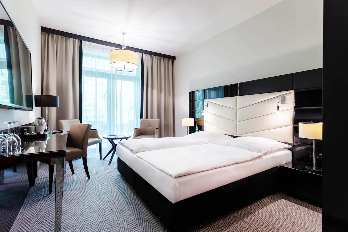 Une chambre d’hôtel moderne équipée d’un grand lit, d’un bureau avec une chaise, d’une petite table et d’un téléviseur.