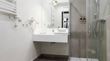 Une salle de bain moderne avec une douche à parois de verre, un lavabo blanc avec un miroir et un porte-serviettes.