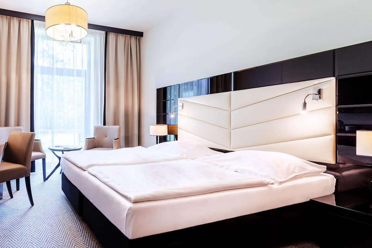 Une chambre d’hôtel avec un grand lit, un bureau, une chaise et une fenêtre avec des rideaux.