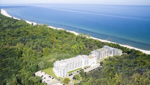 An aerial view of a coastal hotel with multiple buildings, a parking lot, and a beach. - Diune Resort (Kolobrzeg)