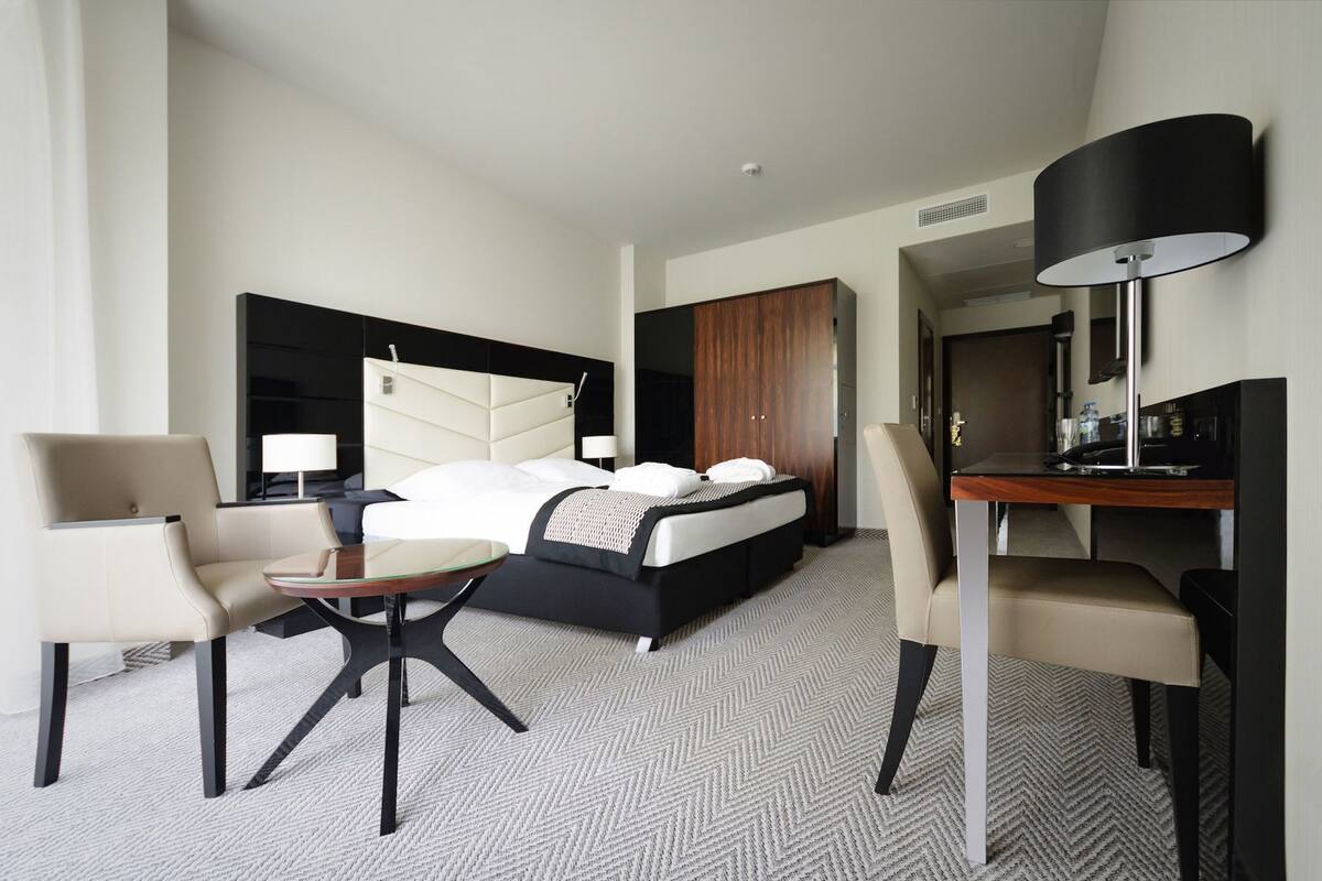 Une chambre d’hôtel comprenant un lit, deux chaises, un bureau, une lampe et une armoire.