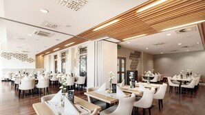 A spacious restaurant with multiple tables and chairs, wooden flooring, and modern ceiling design. - Diune Resort (Kolobrzeg)