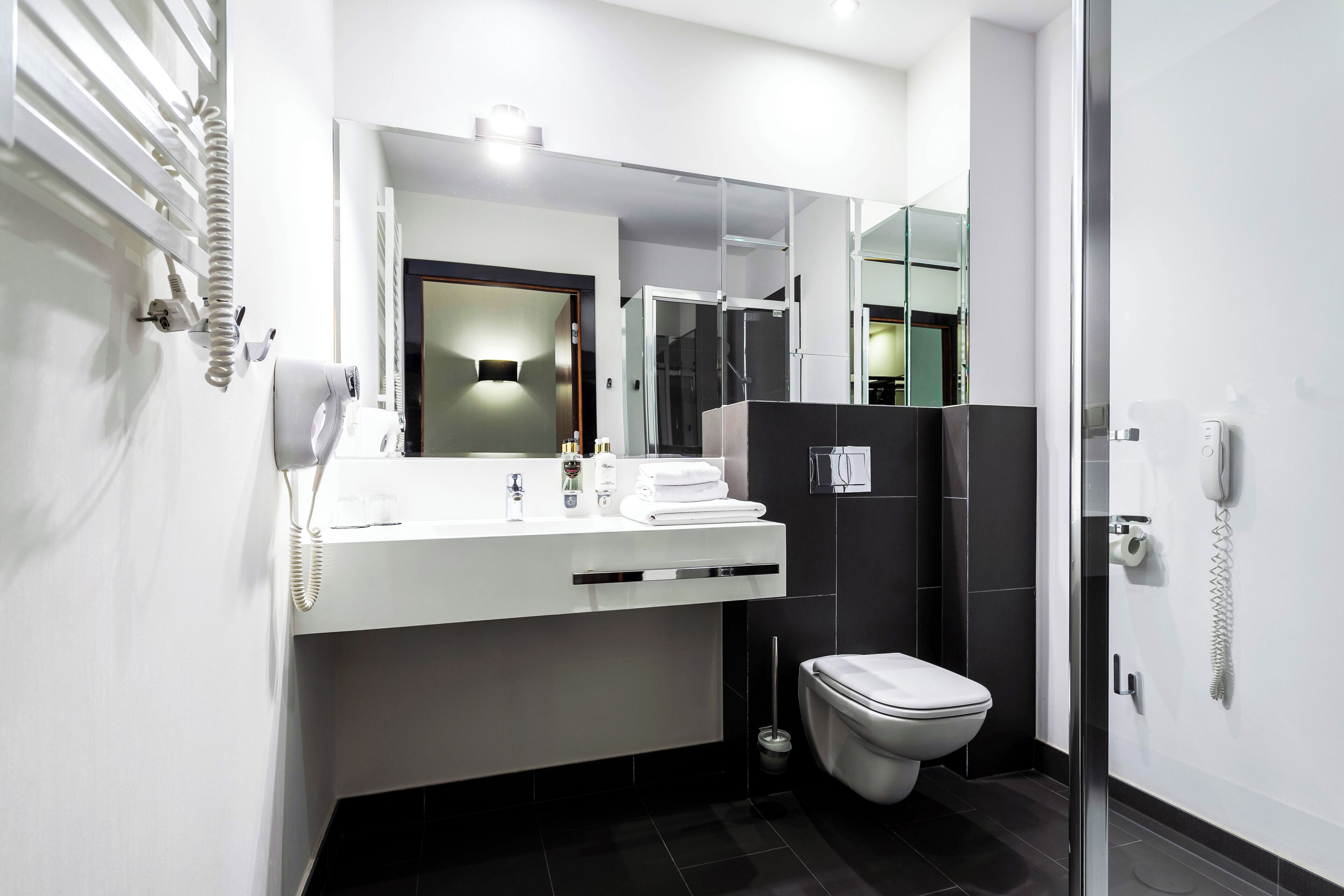 A modern bathroom with a white vanity, a glass shower enclosure, and a toilet.