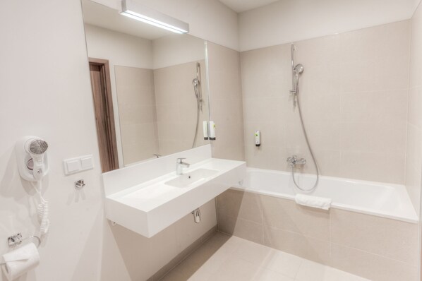 A modern bathroom with a white sink, a mirror, a shower, and a hairdryer.