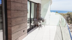Ein Balkon mit Tisch und Stühlen, Holzvertäfelung und einer Glastür, die zu einem Außenbereich führt.