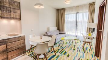 Una habitación de hotel moderna con sofá, una mesa de comedor y una pequeña cocina.