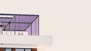 Ein modernes, mehrstöckiges Gebäude mit flachem Dach, großen Fenstern und einem Balkon.