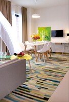 A hotel room with a dining area, a TV, and a colorful striped carpet.