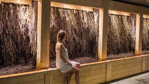 Eine Person sitzt auf einer Bank in einem Raum mit Holzwänden und einer Decke mit sternförmigen Lichtern.