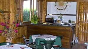 Un intérieur en bois comprenant un coin repas, un comptoir de cuisine et un luminaire décoratif en forme de soleil.