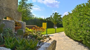 Un chemin de pierres mène à un bâtiment doté d’un jardin de cactus et d’une enseigne.