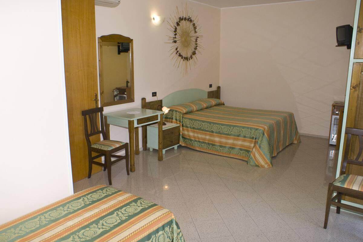 A bedroom with two beds, a desk, a chair, and a mirror.