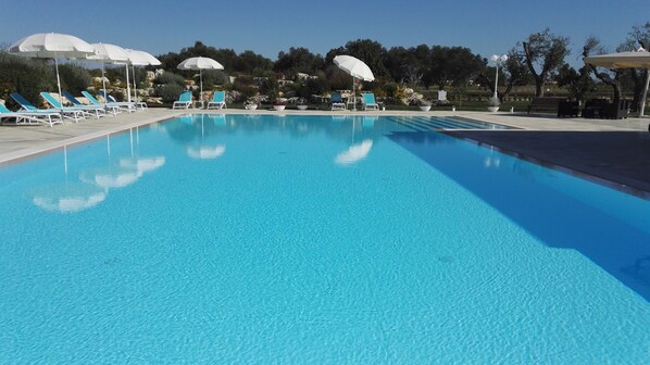 A clear blue swimming pool with lounge chairs and umbrellas. - Agriturismo Li Damiani (Otranto)