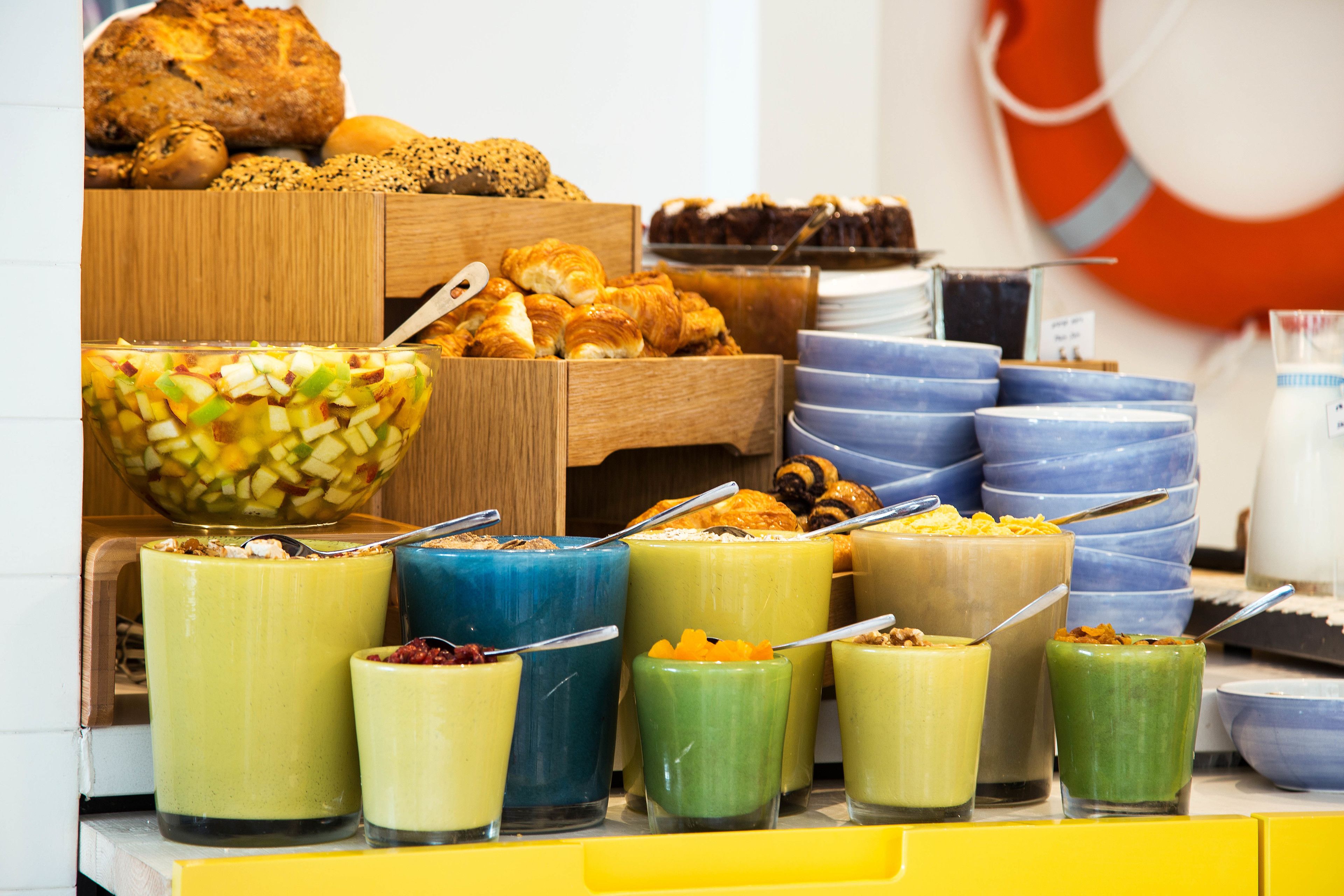A buffet with various food items including pastries, fruits, and colorful smoothies.