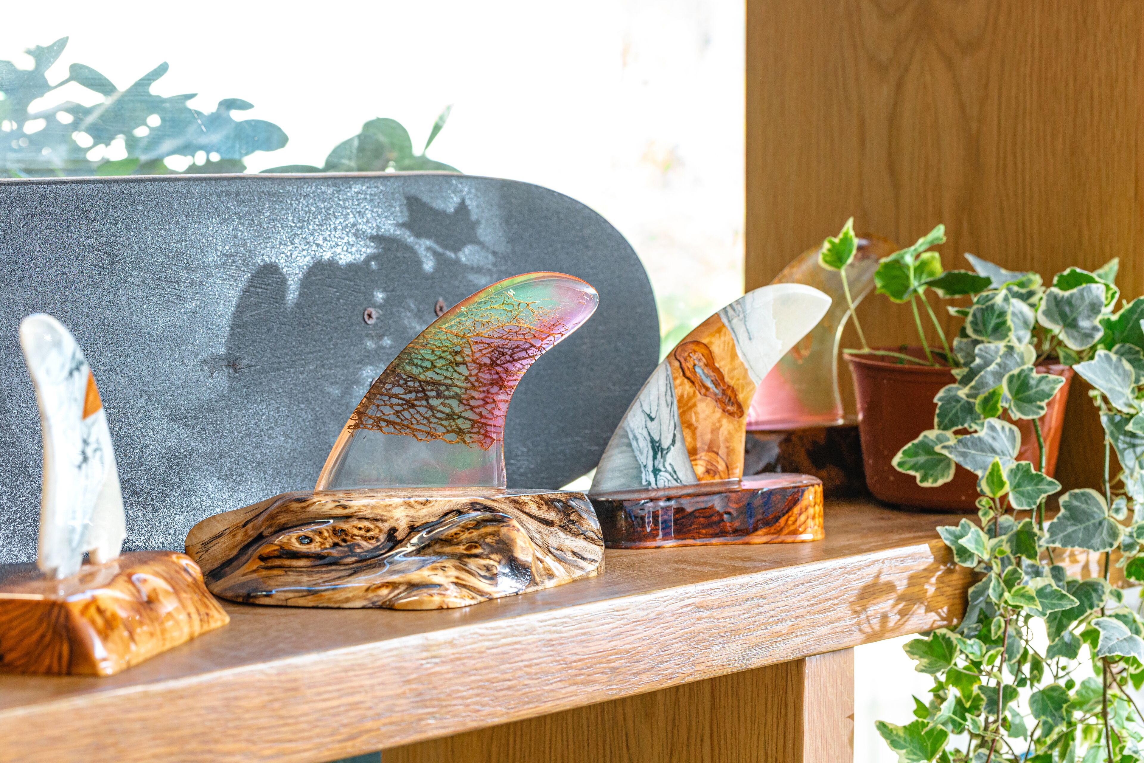 Una estantería de madera con objetos decorativos, incluyendo un monopatín, una cuchara y una planta.