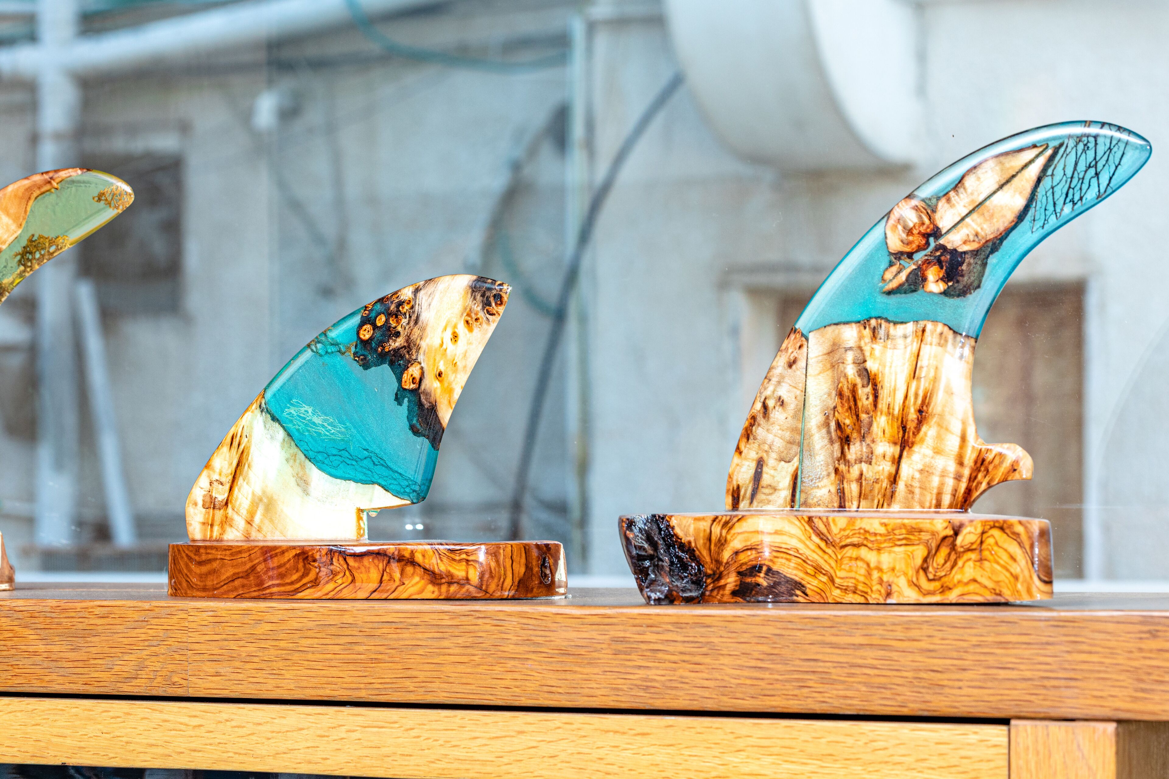 Deux sculptures en bois ornées de touches de turquoise, posées sur une table en bois.
