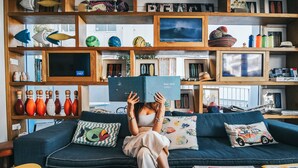 Una sala de estar acogedora con un sofá azul, una mesa de centro con una taza y una estantería llena de objetos varios.